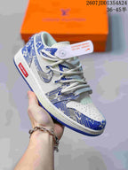 Angled side view of the blue and white Nike Dunk Low Retro sneaker showing the patterned overlays, white midsole, blue outsole, and attached tag.