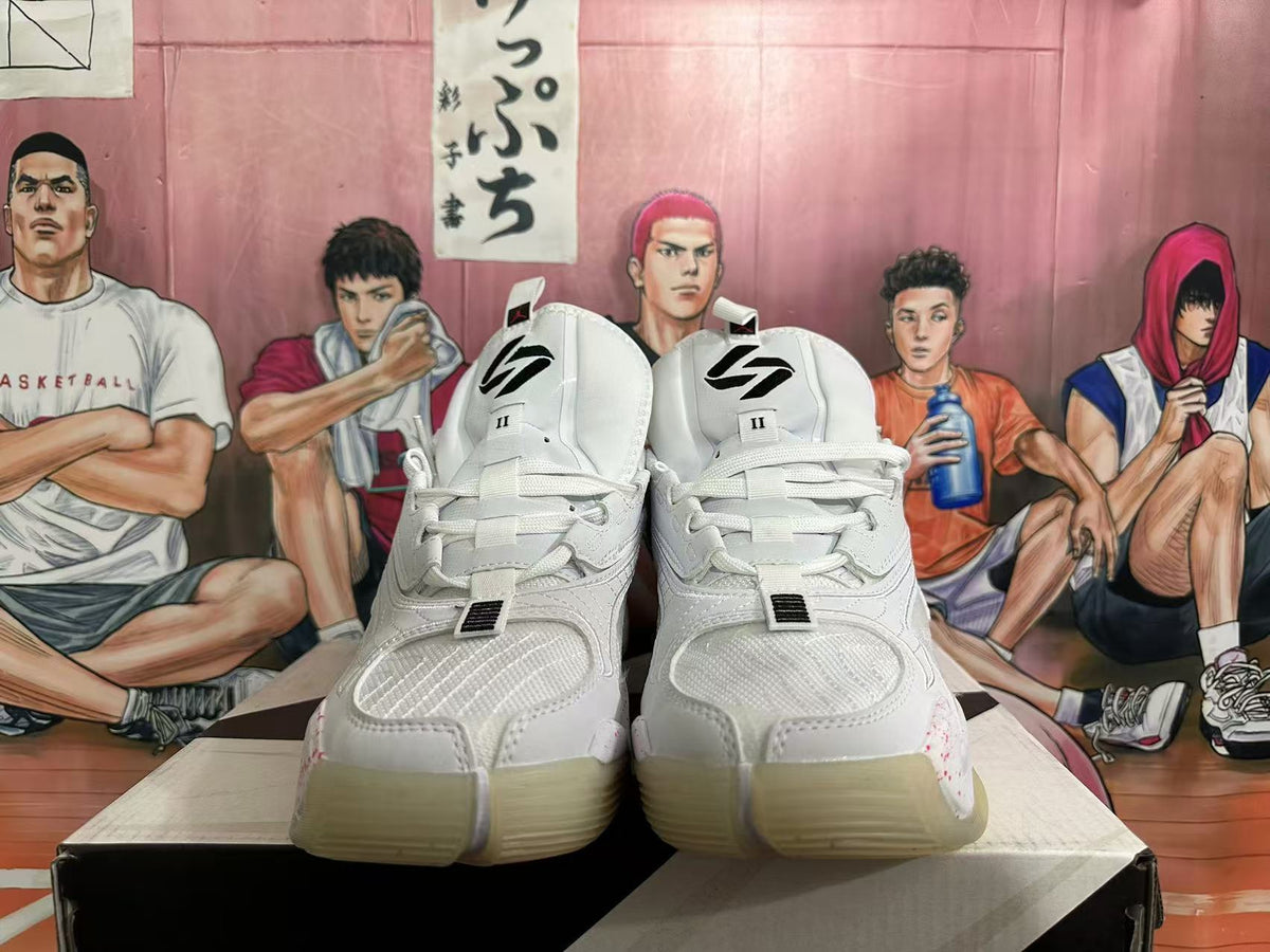 Front view of white Jordan basketball sneakers with layered toe panels, white laces and black tongue branding.