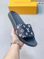Angled view of the black slide sandal showing the patterned strap, open toe, and raised sole.