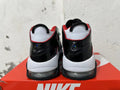 Rear view of white and black Nike sneakers with red trim and visible sole cushioning.