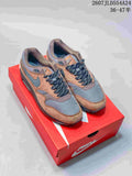Pair of brown and grey Nike Air Max 1 sneakers displayed on a red Nike shoebox.