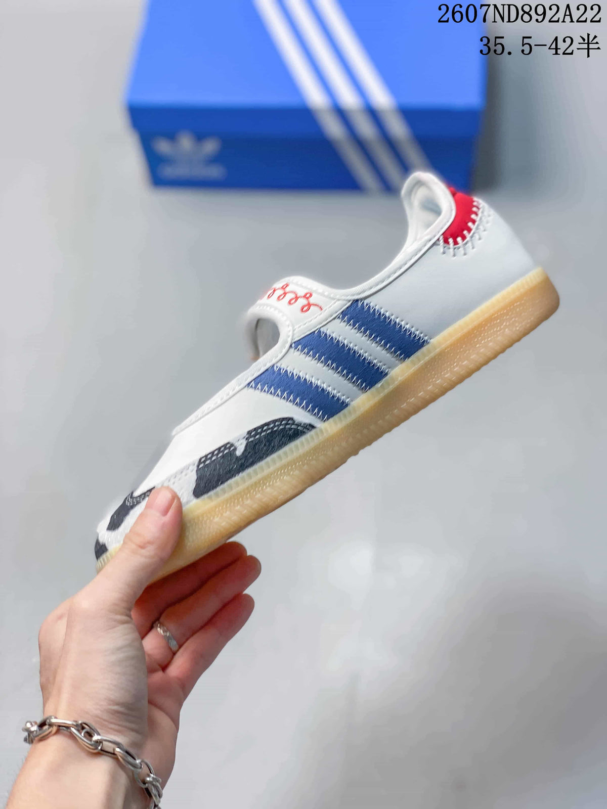 Side view of the sneaker showing blue side stripes, a white upper, patterned toe panel, and gum-colored sole.