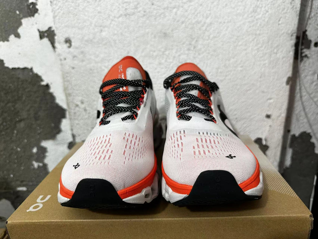 Front view showing white sneaker toes, orange-red tongues, and black dotted laces