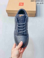 Front view of a dark gray Nike Dunk Low sneaker with perforated toe