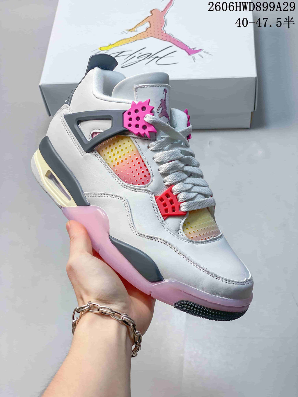 Three-quarter view of the white and gray sneaker with pink accents and translucent outsole sections.