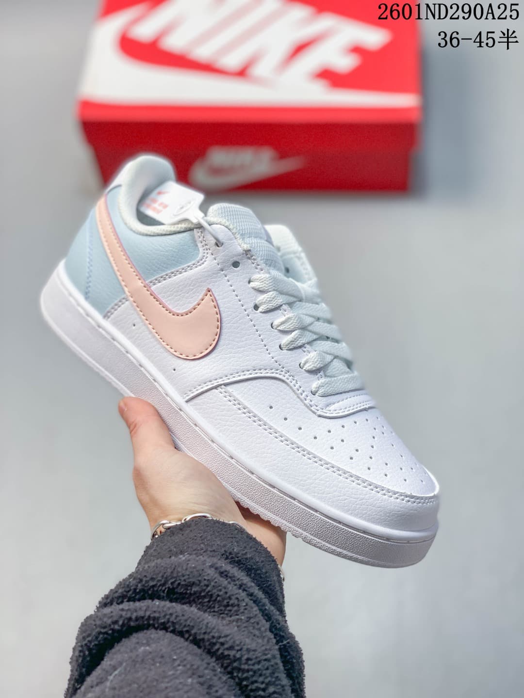 Close-up of a white low-top sneaker with pale blue heel panels and a pale pink Swoosh.