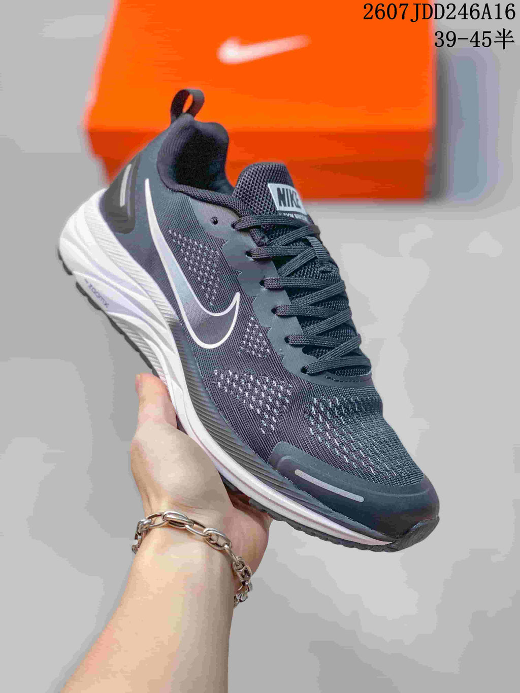 Close side view of a dark gray sneaker with a white Swoosh, mesh-style upper, laces, and white layered midsole.