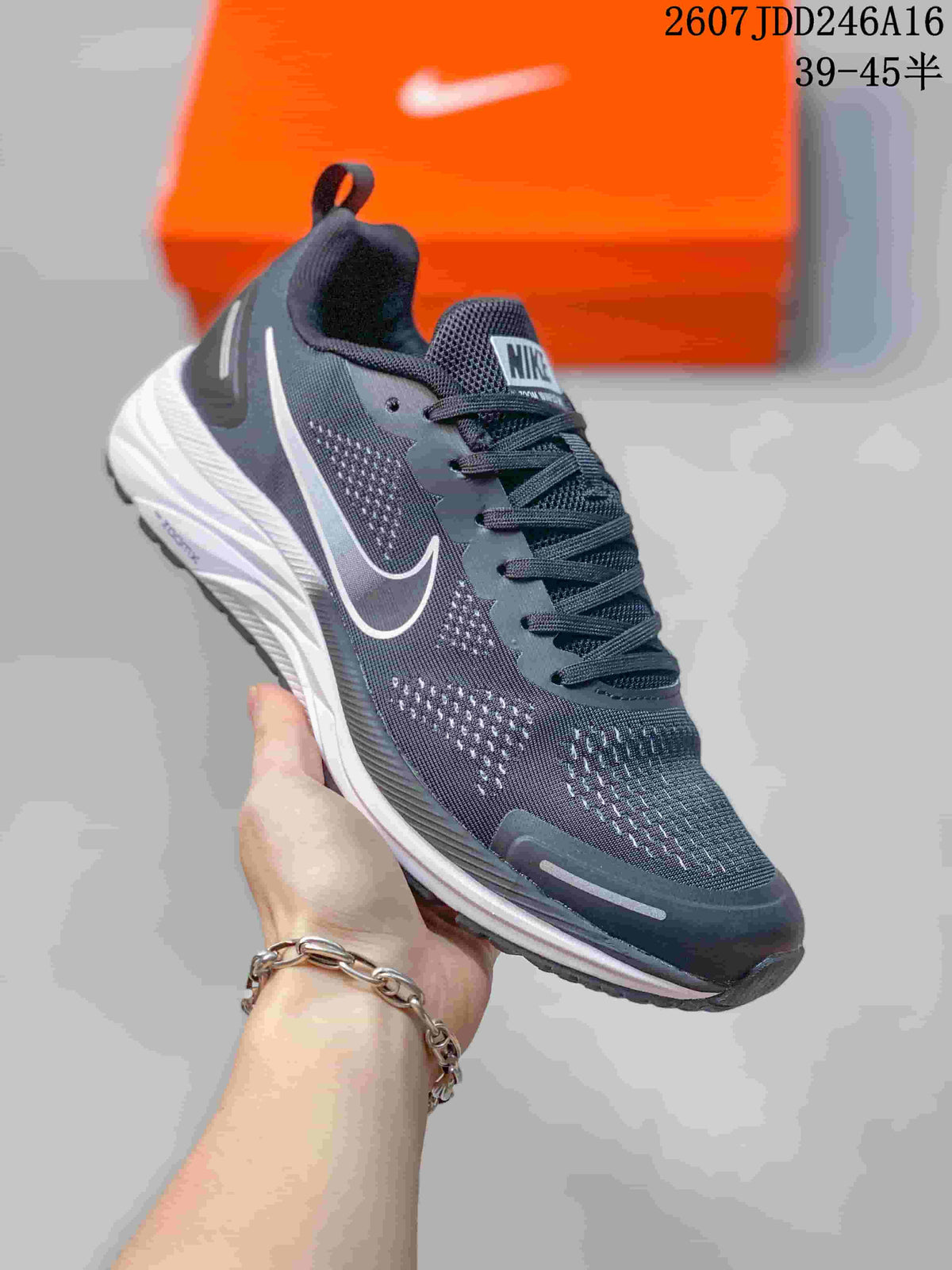 Close side view of a dark gray sneaker with a white Swoosh, mesh-style upper, laces, and white layered midsole.