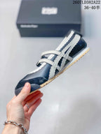 Side view of the navy and white sneaker showing the buckle straps, side stripes and low-top profile.
