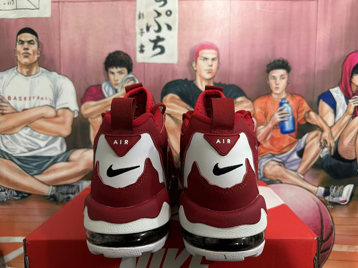 Rear view of red and white Nike sneakers showing black swoosh logos, heel branding, and a visible heel window.