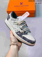 Hand-held side view of a white sneaker with pale green and indigo patterned sections and white laces.