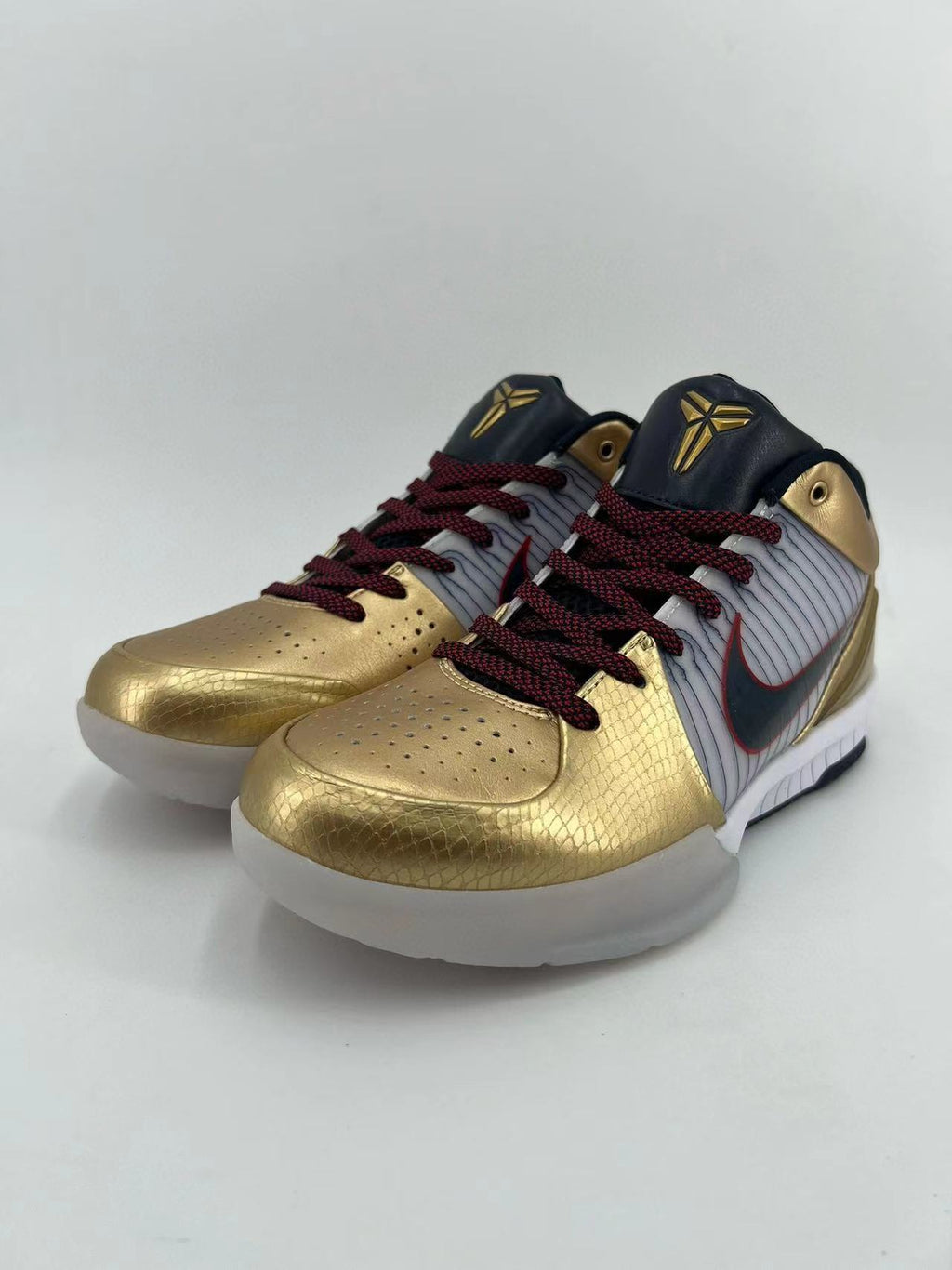Pair of gold, white, and black low-top basketball sneakers shown from the front three-quarter angle.