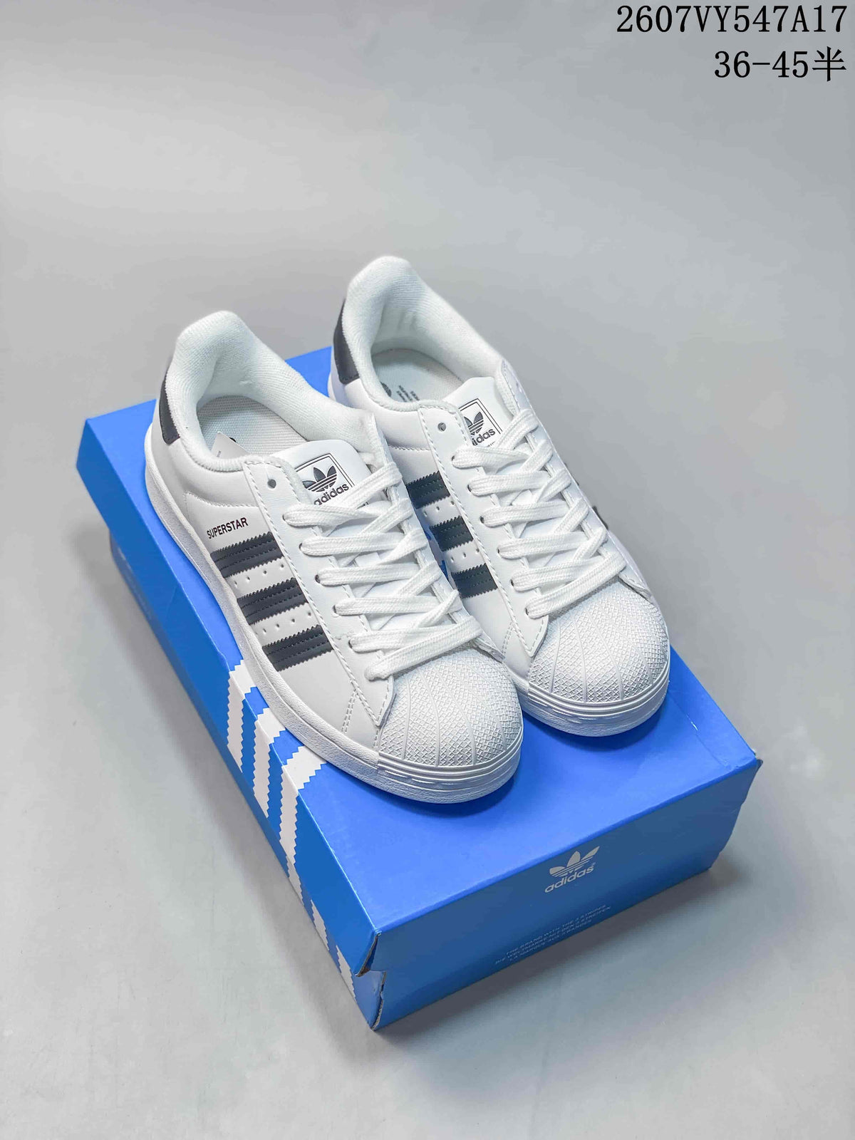 White adidas Superstar sneakers with dark stripes and a blue adidas shoebox; image text shows style code 2607VY547A17 and size range 36–45.5.