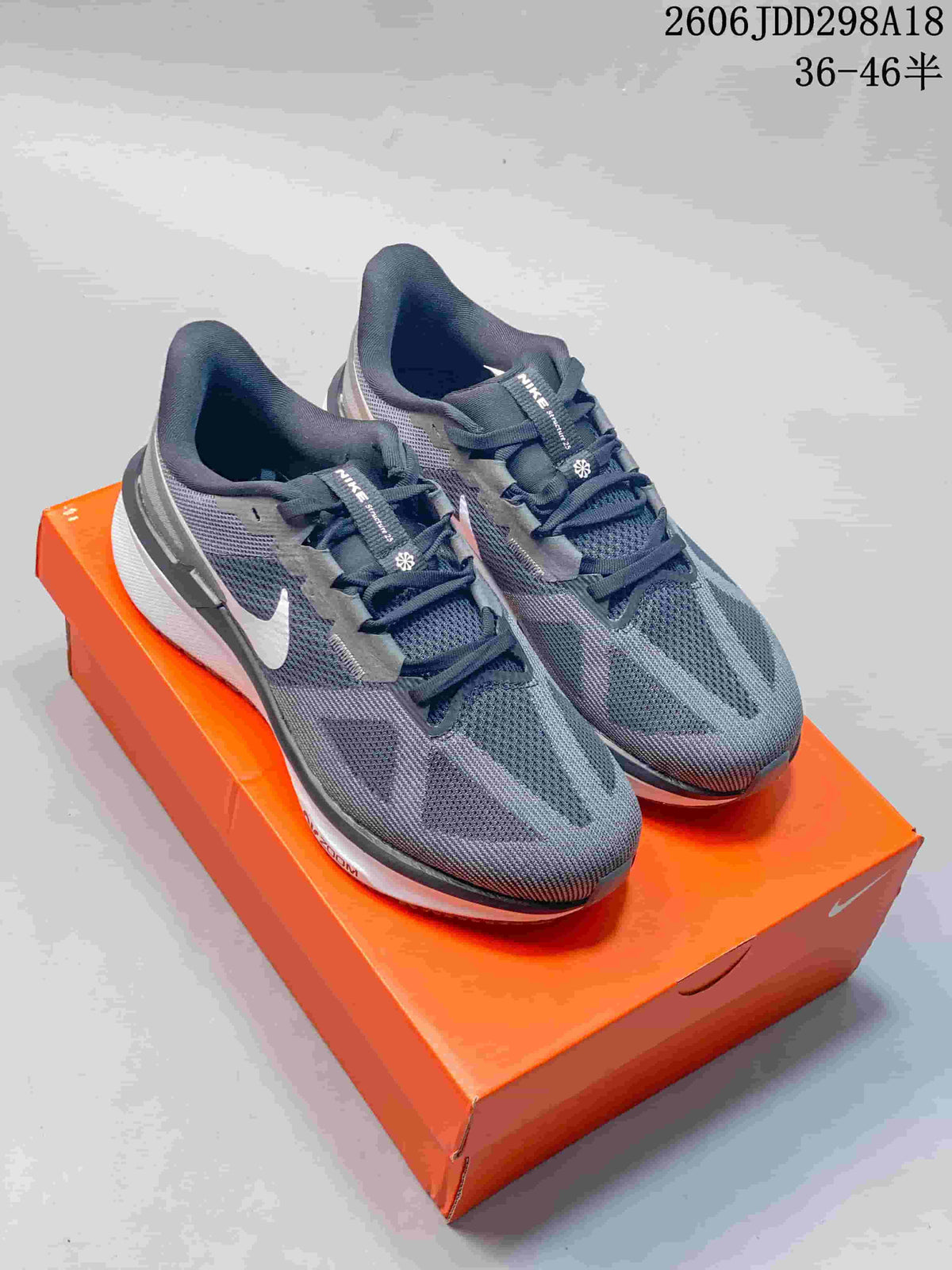 Pair of dark gray Nike ReactX running shoes with white side logos on an orange shoe box.