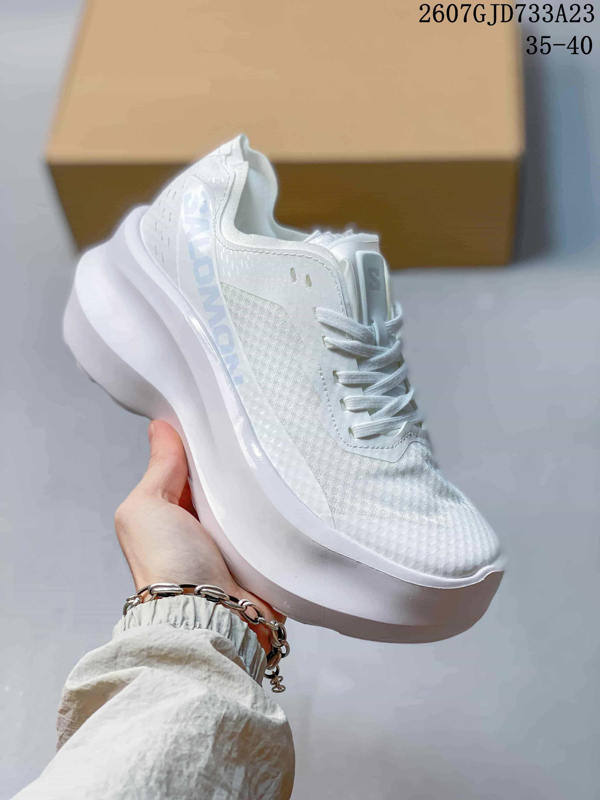 Close side view of a white Salomon sneaker showing the upper, side branding and thick sculpted sole.