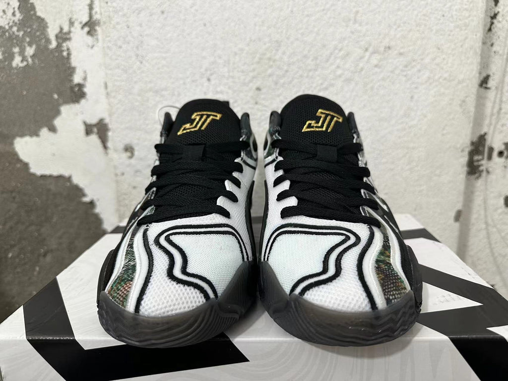 Front view of white and black sneakers with black laces and gold tongue embroidery