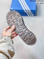 Close-up of the sneaker outsole showing a dark tread pattern with circular details and trefoil-style motifs.
