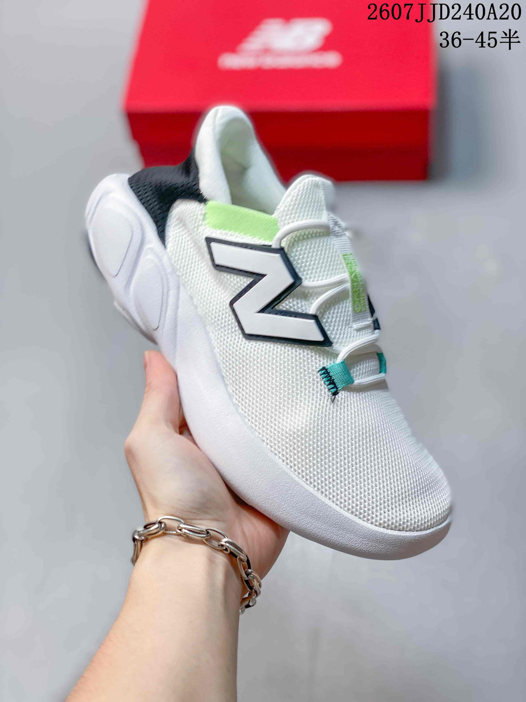 Angled side view of the white New Balance sneaker showing the large N logo, black heel collar, light green accent and rounded white outsole.
