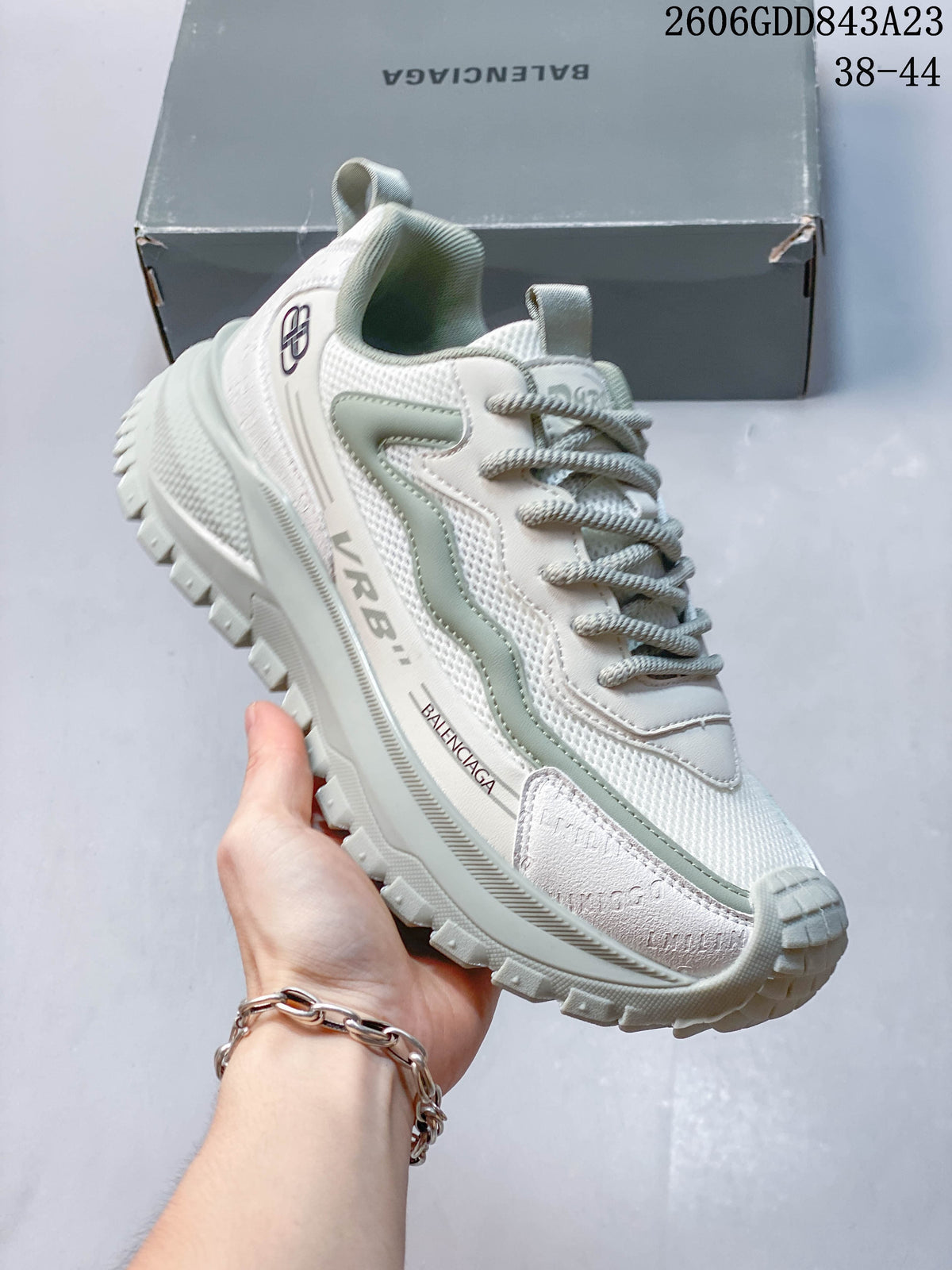 Angled view of the white and pale sage chunky sneaker with visible side branding and outsole.