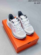 Pair of white and pink Nike Quest 6 running shoes displayed on an orange shoebox.