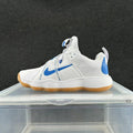 Side view of a white Nike sneaker with blue accents, printed strap detail, and gum-colored outsole.