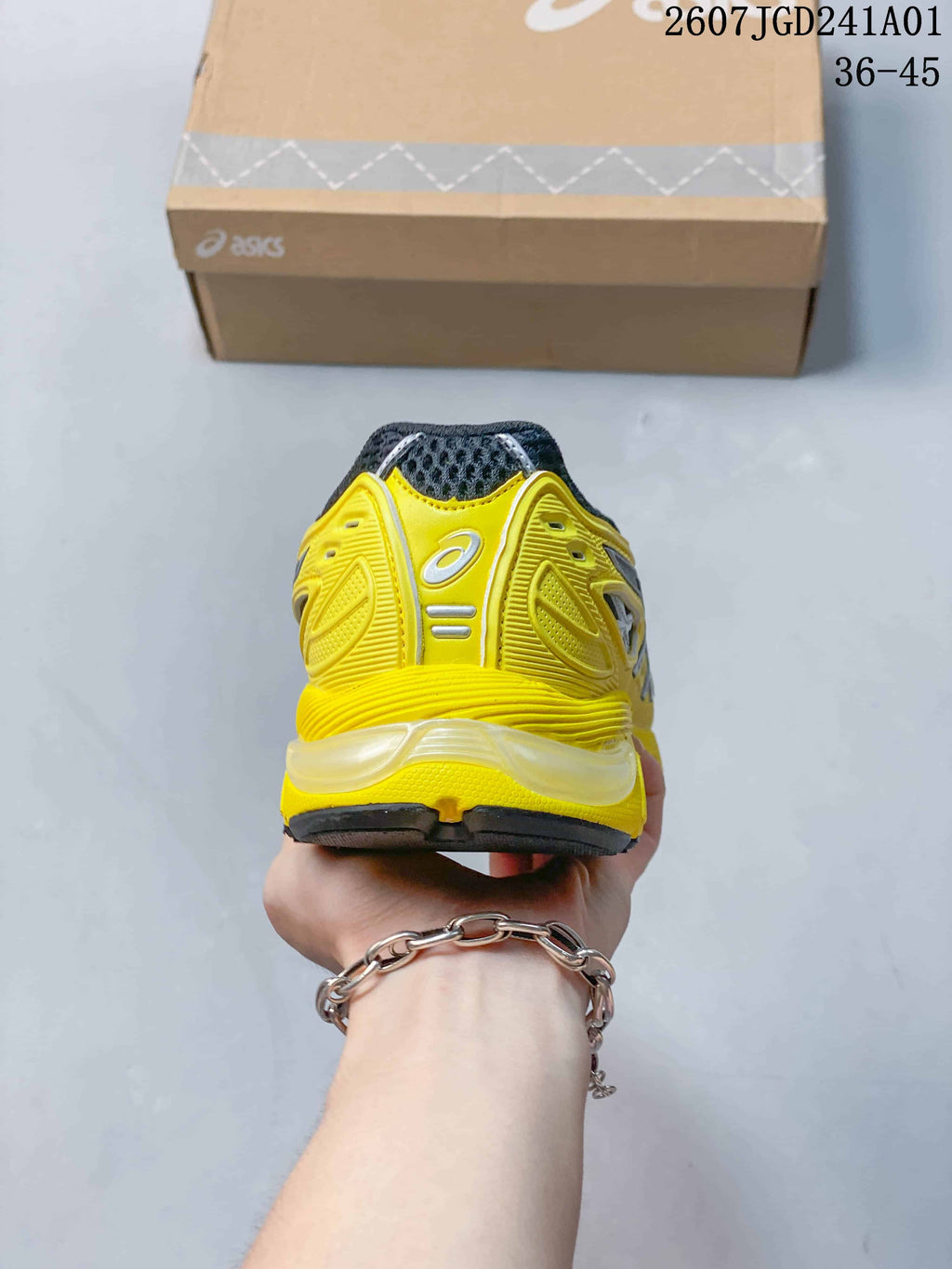 Rear view of the yellow ASICS sneaker with a charcoal heel collar.
