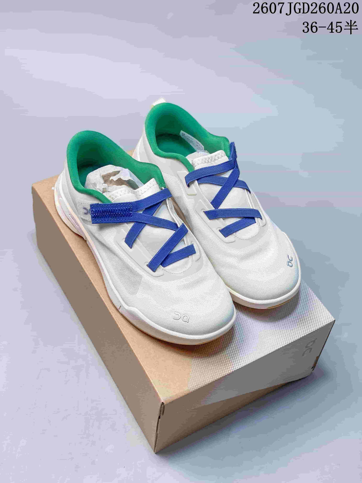Pair of white On Cloudnova Moon sneakers with bright blue straps and green collars displayed on a shoebox.