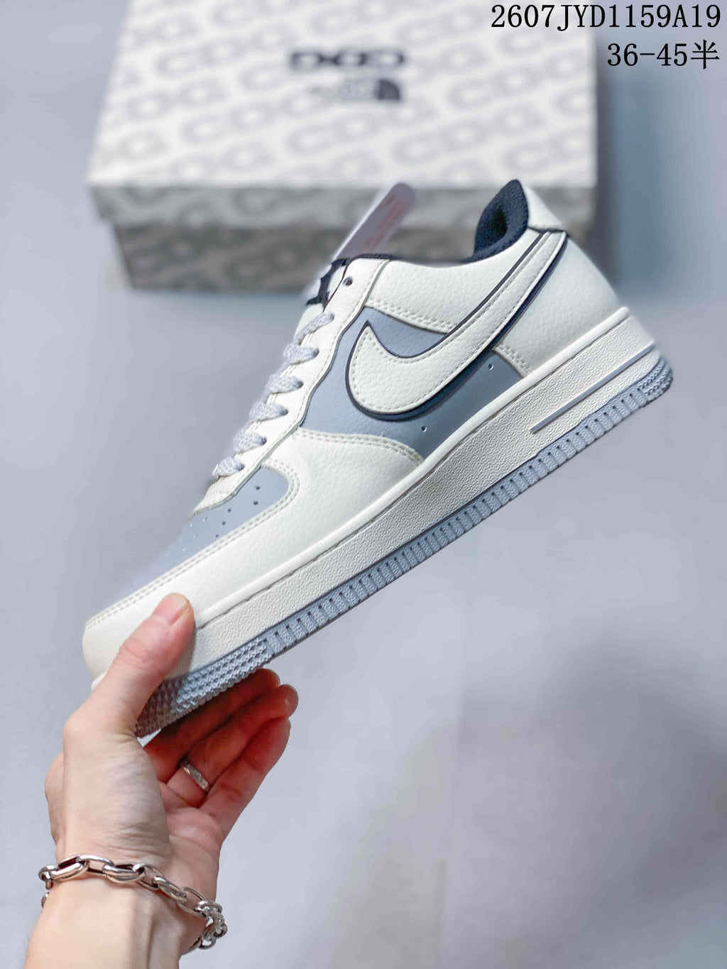 Side profile showing the white and gray upper, layered panels, low-top collar, and textured outsole.