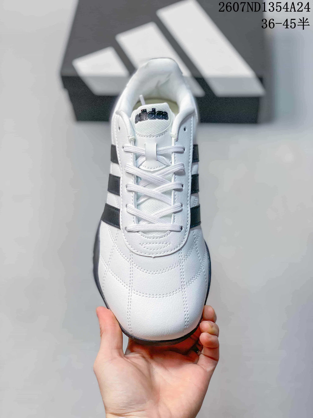 Top view of the lace-up sneaker showing the white upper, tongue branding and black side stripes.