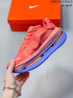 Side view of a coral Nike running shoe with textured upper, black Swoosh, and blue-orange sole.