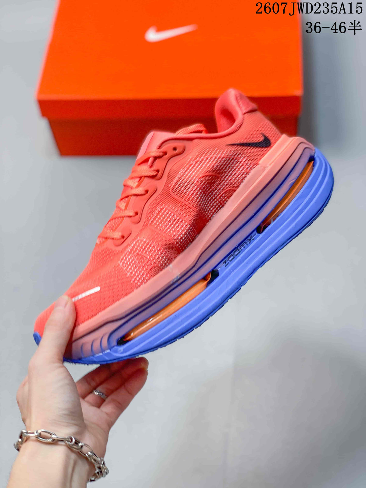 Side view of a coral Nike running shoe with textured upper, black Swoosh, and blue-orange sole.