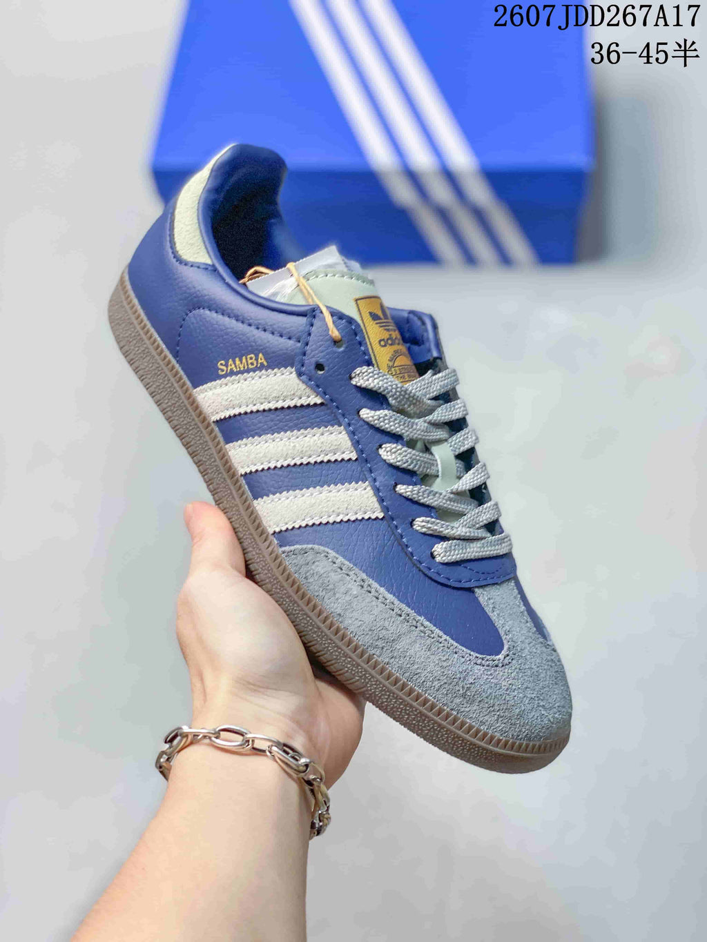 Angled side view of the blue adidas Samba sneaker with white stripes, gray toe panel, and gum-colored sole.
