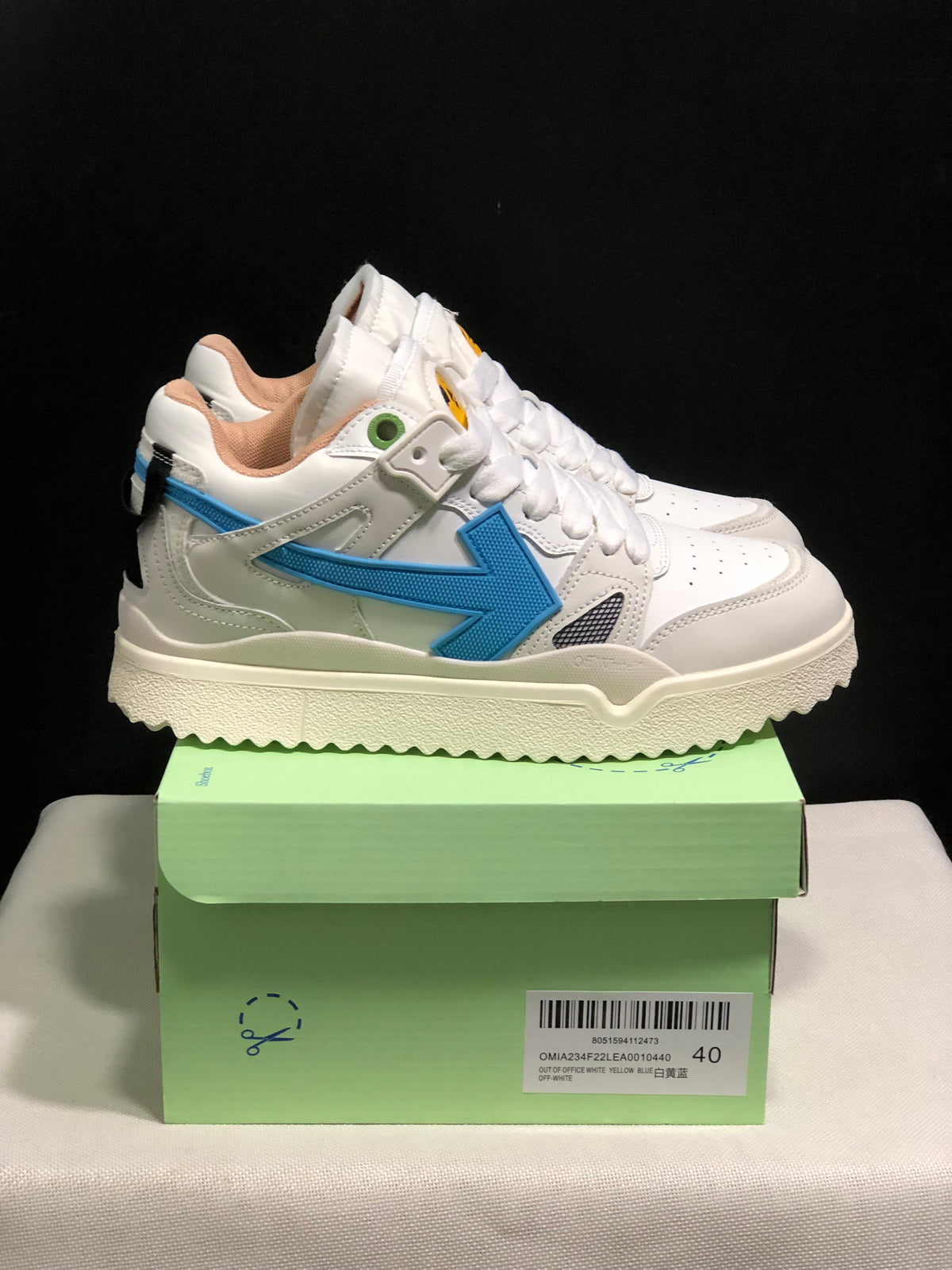 Side view of the white sneakers showing the blue arrow detail, padded collar, and textured outsole.