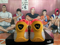 Rear view of coral pink and gold PUMA All-Pro basketball shoes on a black shoebox.