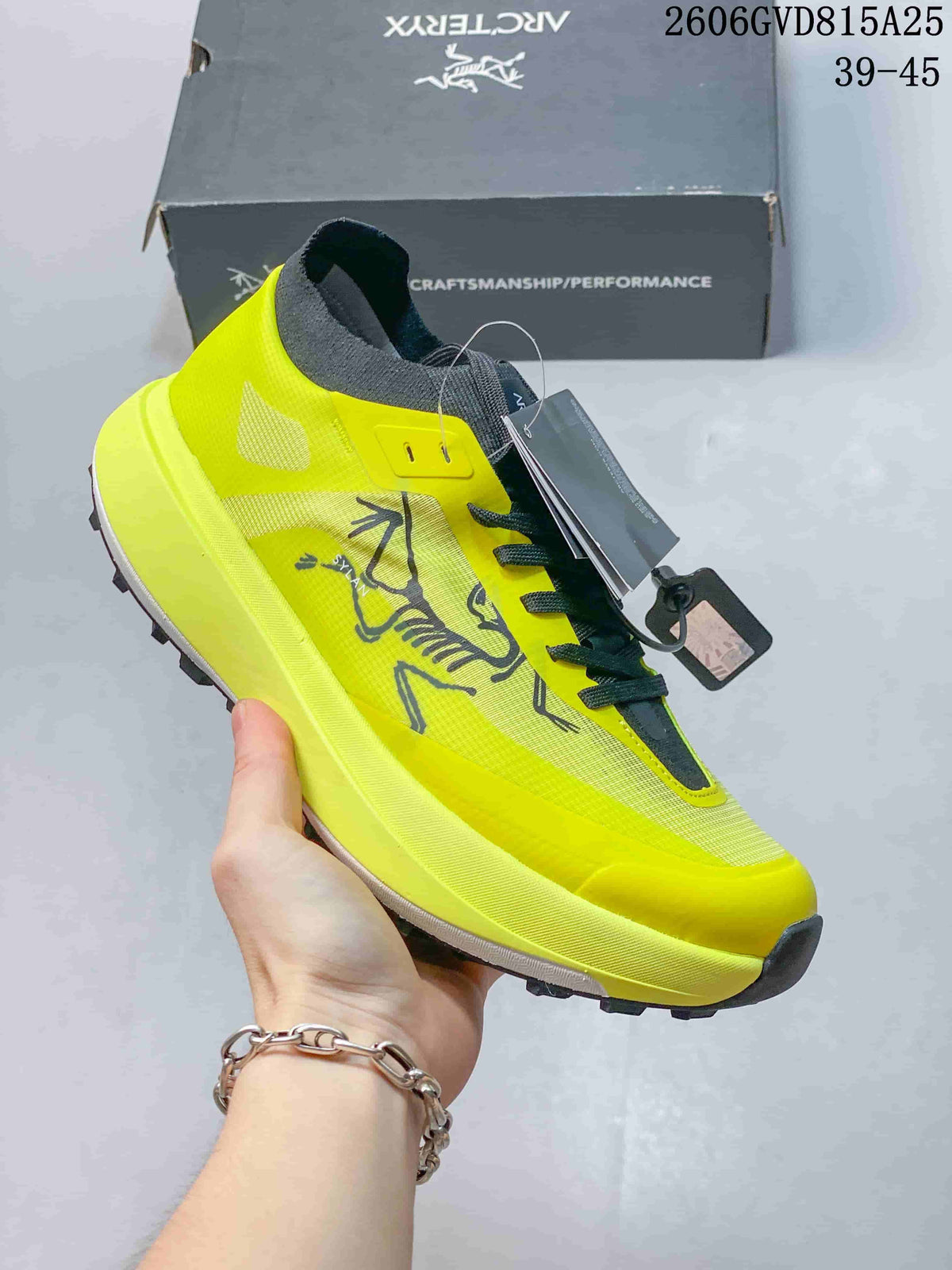 Side view showing the shoe's yellow upper, Arc'teryx graphic, and lugged outsole