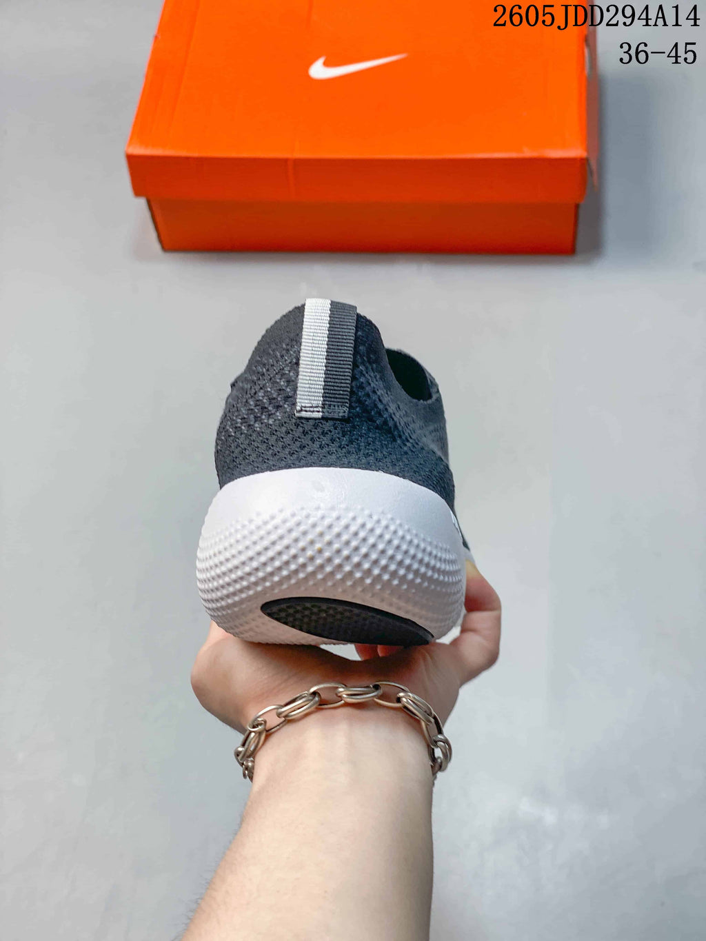 Rear view of a dark gray Nike Free sneaker showing the heel pull tab, textured upper, and white sculpted sole.