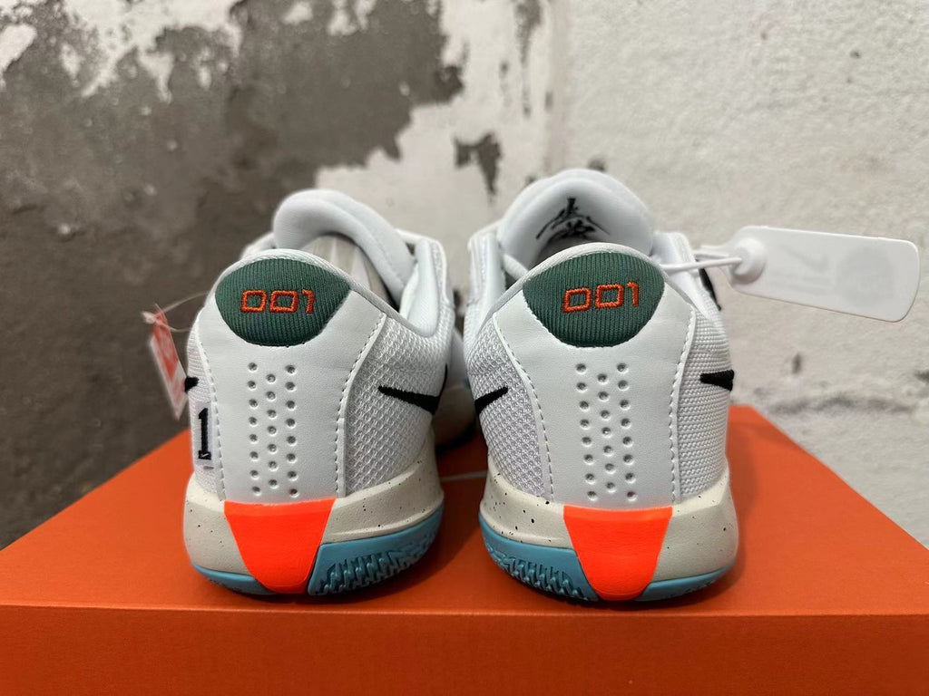 Rear view of white Nike basketball shoes with green heel tabs, orange heel accents, and blue outsoles