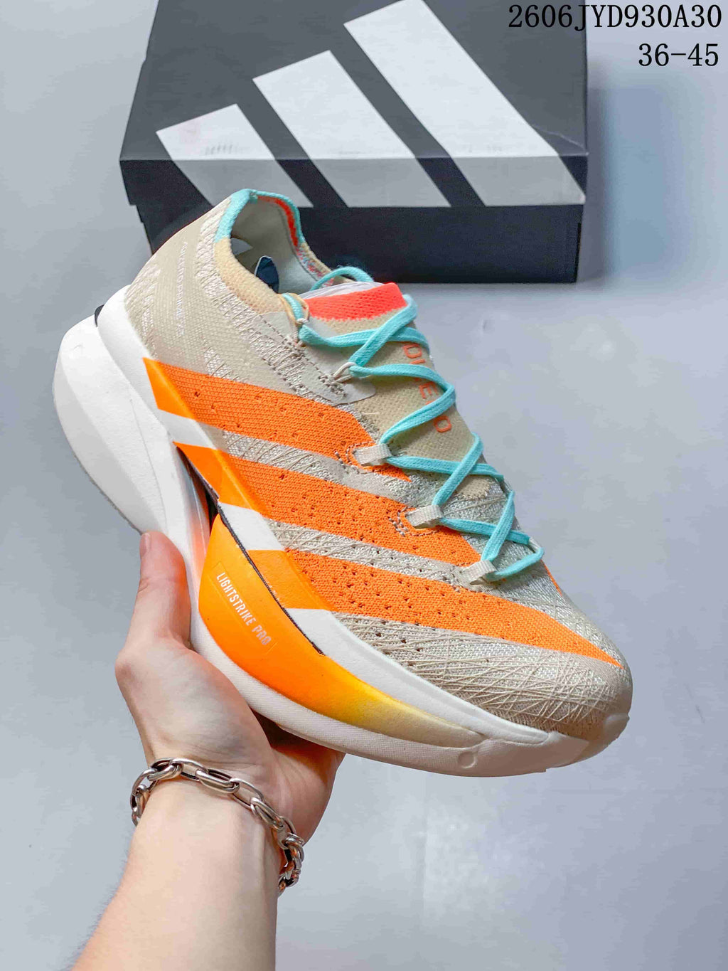 Side profile of a beige running shoe with orange accents and turquoise laces