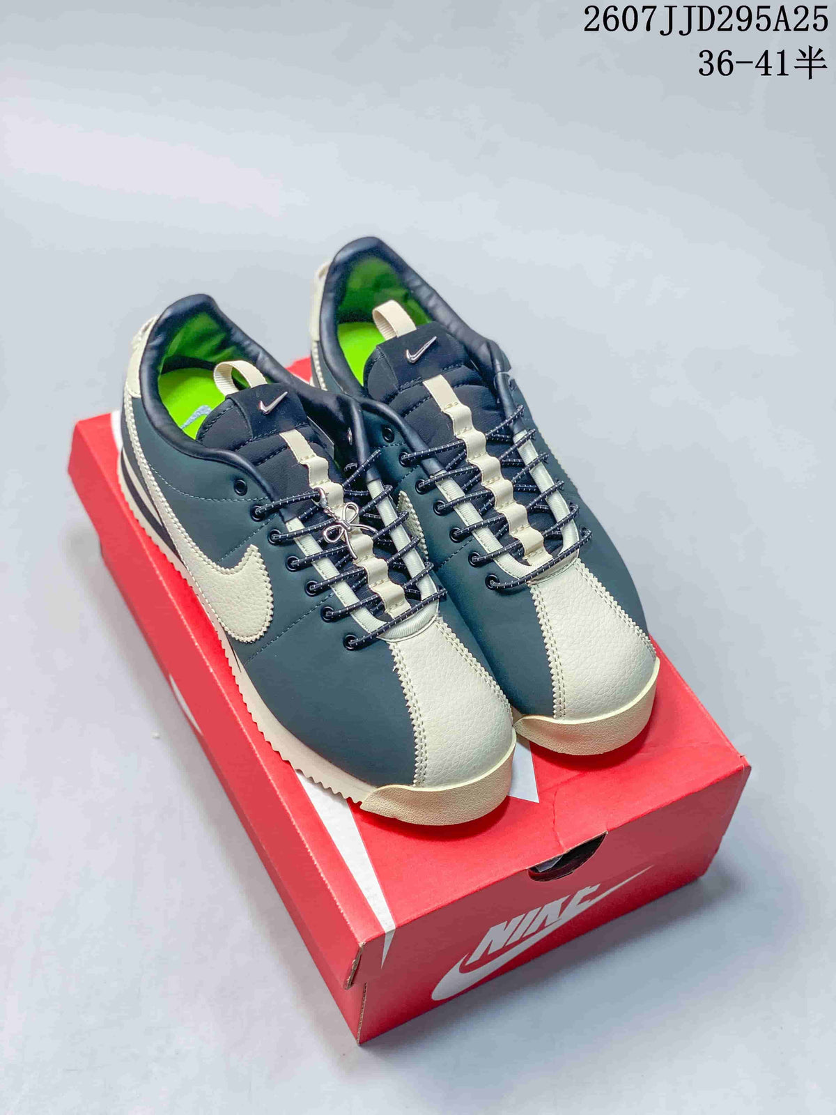 Pair of navy and cream Nike sneakers displayed on a red shoebox, showing the contrast toe panels, laces, side Swooshes, and visible style code.