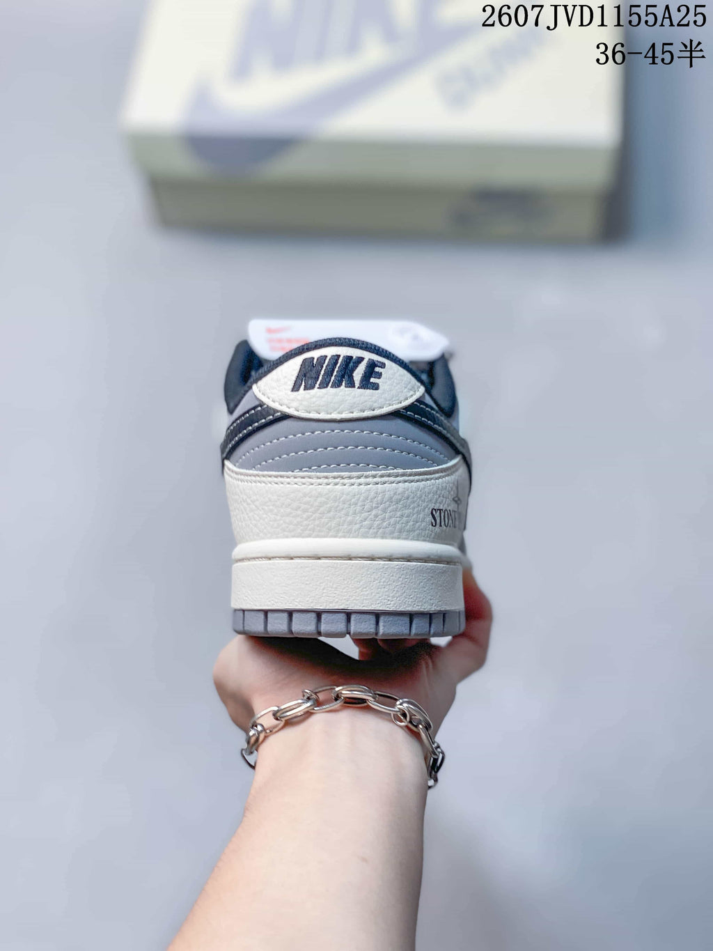 Rear view of the Nike SB Dunk Low Pro sneaker showing white and grey panels, dark navy collar details and heel branding.