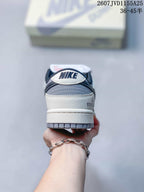 Rear view of the Nike SB Dunk Low Pro sneaker showing white and grey panels, dark navy collar details and heel branding.