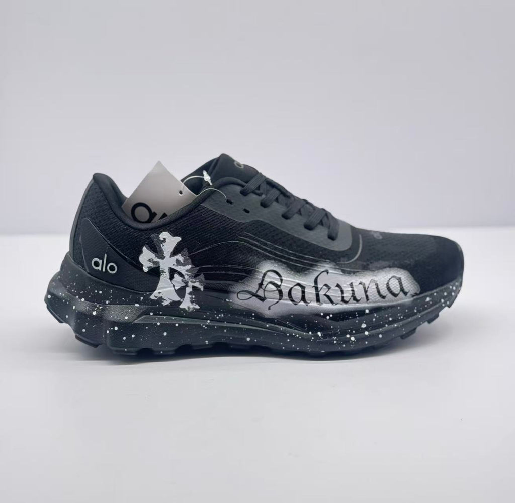 Side view of black alo sneakers with white Sakura graffiti artwork and a speckled sole.