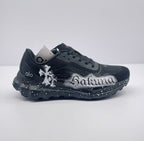 Side view of black alo sneakers with white Sakura graffiti artwork and a speckled sole.