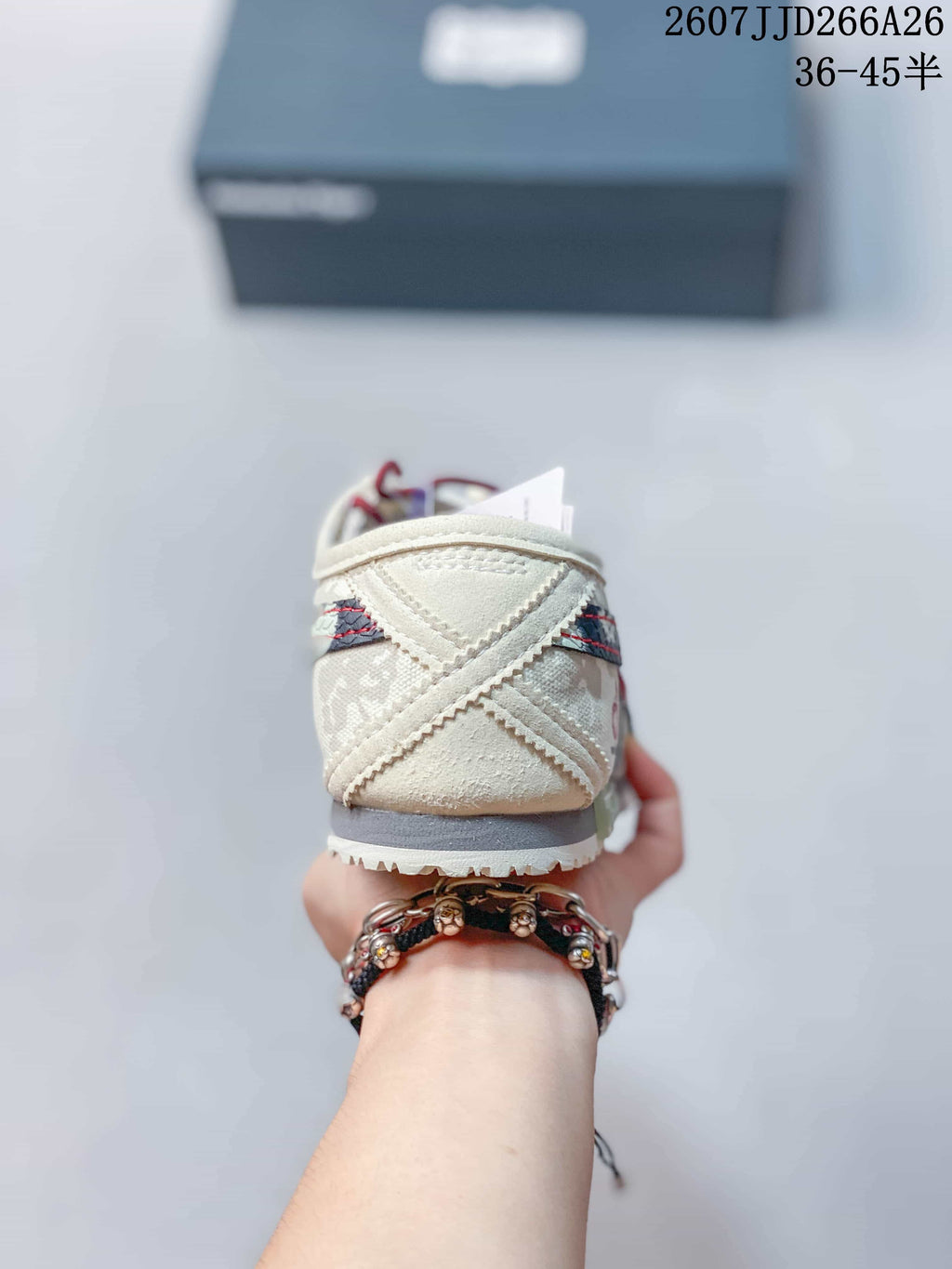 Rear view of the cream sneaker showing layered heel panels, contrast stitching, and a dark outsole edge.