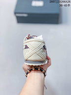 Rear view of the cream sneaker showing layered heel panels, contrast stitching, and a dark outsole edge.