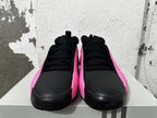 Front view of black lace-up sneakers with bright pink sides and blue outsole accents.