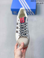 Top view of the sneaker showing the shell toe, braided laces, dark tongue, and red adidas label.