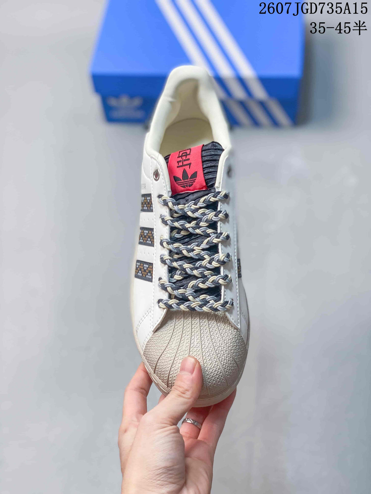 Top view of the sneaker showing the shell toe, braided laces, dark tongue, and red adidas label.