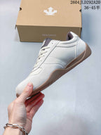 Side profile of a cream Descente low-top sneaker with textured panels and a gum-colored sole.