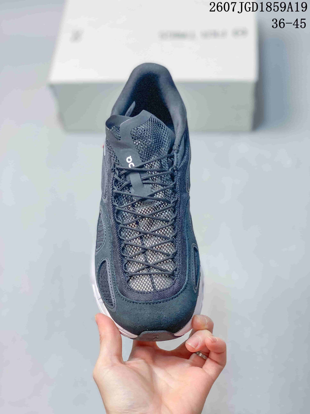 Front view of the black sneaker showing the mesh tongue, lace system, rounded toe, and white outsole edge.